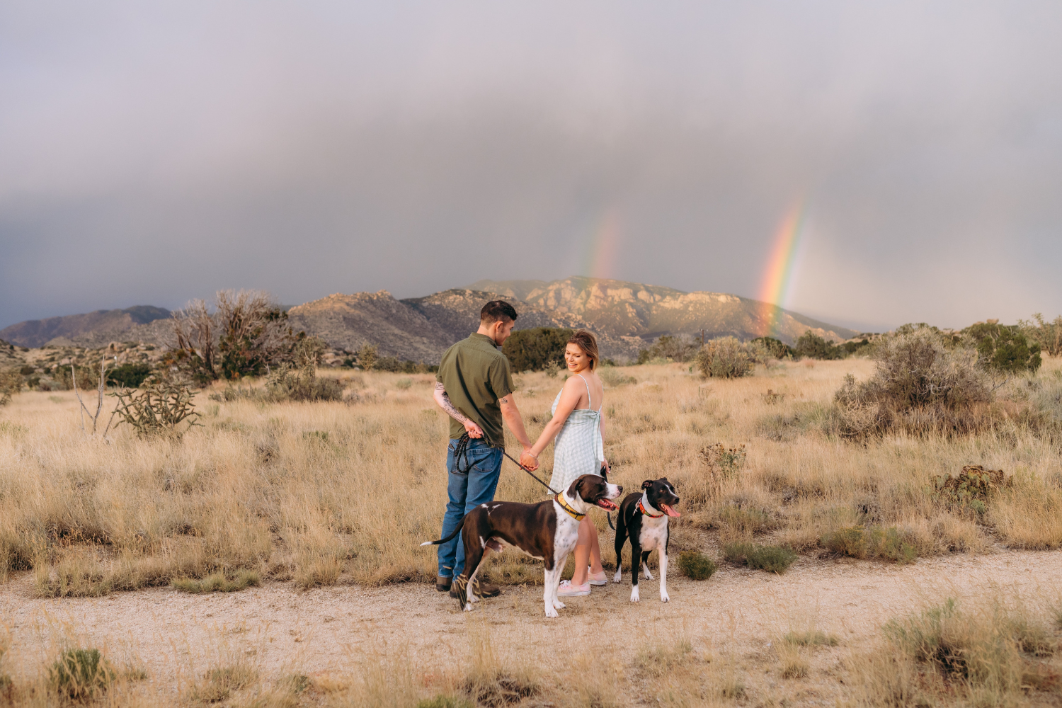 Family with two dogs in front of a rainbow in the Manzano Foothills